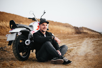 Obraz premium Smiling happy biker in sitting on motorcycle on road