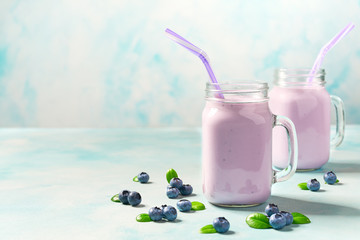Glass jar mugs with blueberry smoothie with fresh blueberry on a light background, with copy space