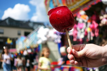 sweet candy apple on county fair or festival. red candy apple covered in red caramel, at holiday vacation event or amusement park