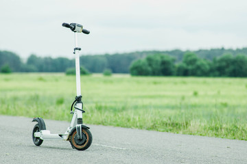 White modern electric scooter on asphalt road. environmental transport concept