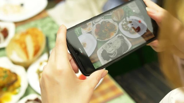 Female hands make photo on a smartphone in a restaurant with dishes of Caucasian cuisine. grilled vegetables, shashlik, sauce