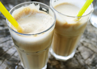 Two glasses with creamy ice coffee on wooden table 