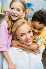 cute kids hugging happy woman standing near adorable boy