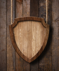 Fototapeta premium Defense protection shield shaped sign hanging on ropes with wood planks background