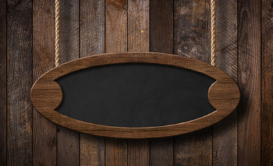 Oval blackboard hanging on ropes with wood planks background