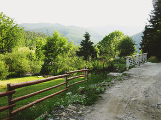 Fototapeta na wymiar Old road with wooden fence. Nature forest and mountain