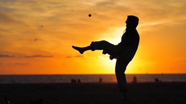 VENICE BEACH, SANTA MONICA, LOS ANGELES, California. A juggler practicing at sunset on a warm day in Southern California. A young man on the beach at dusk. Slow Motion.