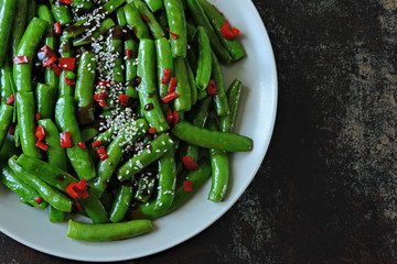Green pea pods with chili pepper and sesame. Asparagus beans on a plate in the Chinese style. Vegan food. Healthy lunch. Diet food.