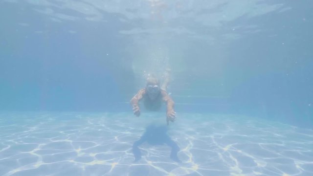 Adult man in mask swimming under blue water floating pool and showing thums up. Portrait cheerful man smiling and swimming in water pool summer resort hotel
