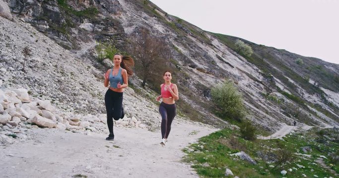 Charismatic and concentrated ladies running through the mountain road in a beautiful summer day with a beautiful landscape