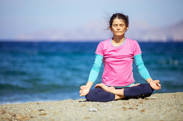 Fototapeta na wymiar Caucasian young woman practicing yoga on beach