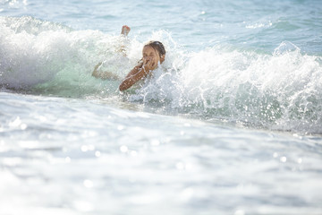 Young girl playing in breaking waves on beach