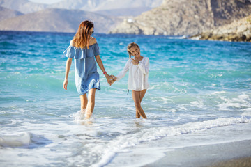 Fototapeta na wymiar Young woman and her daughter enjoying summer day on beach