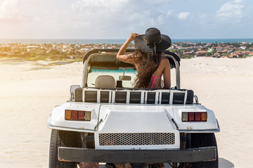 Beautiful happy young woman with buggy ride through the dunes of the coast of Brazil.