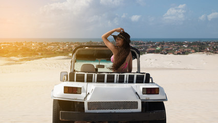 Beautiful happy young woman with buggy ride through the dunes of the coast of Brazil.