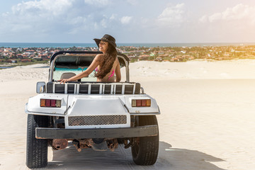Beautiful happy young woman with buggy ride through the dunes of the coast of Brazil.