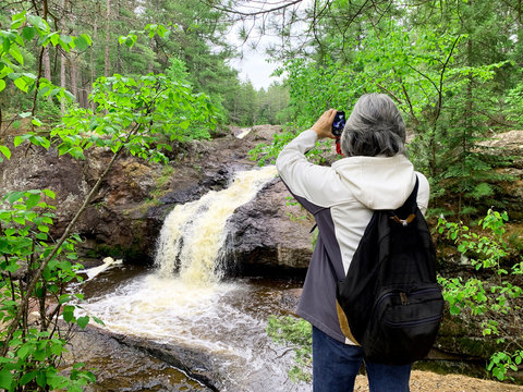 Woman tourist taking waterfall pictures