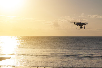 Professional drone silhouette flying near the beach on a summer afternoon