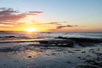 Scenic sunset over the sea. The sun sets on the water. Clouded sky is painted with bright colors. Sunset beach in a summer evening. Brazil.