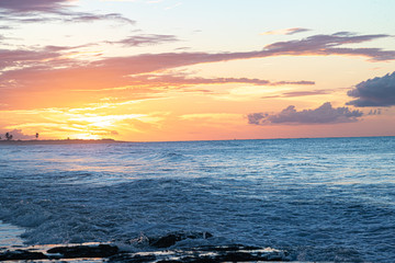 Scenic sunset over the sea. The sun sets on the water. Clouded sky is painted with bright colors. Sunset beach in a summer evening. Brazil.