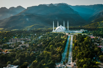 Islamabad / Pakistan - April 25 2019: Aerial photo of Islamabad, the capital city of Pakistan showing the landmark Shah Faisal Mosque and the lush green mountains of the city - obrazy, fototapety, plakaty