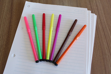 Canetinhas coloridas sobre folha de papel pautada