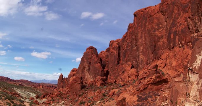 Time lapse of slanted red rock mountain against thin clouds
