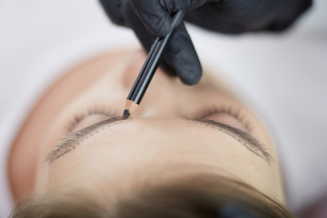 Cosmetologist applying permanent make up on eyebrows
