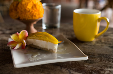 raw vegan cake with cashews and coconut and mango on top on wooden background