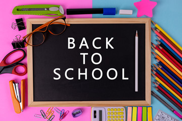 Education, Back to School concept. Various stationary are placed on  pink and blue sky background and blackboard with text "Back to school".