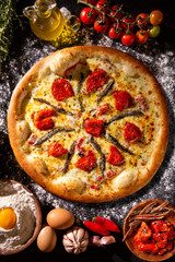 Pizza anchovy and dried tomato on black concrete background. Top view, close up. Traditional Brazilian Pizza.