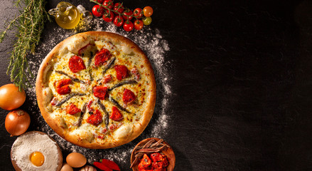Pizza anchovy and dried tomato on black concrete background. Top view, close up. Traditional...