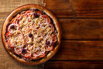 Pizza tuna fish, onion, tomato and black olive on wood background. Top view, close up. Traditional Brazilian Pizza.