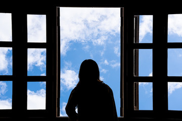 Silhouette woman looking out of window see blue sky and clouds.Freedom concept.