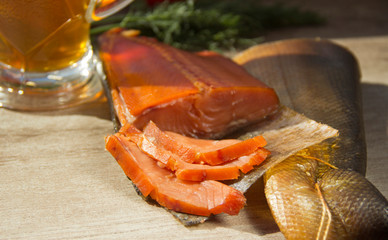 Smoked fish and a glass of beer on a wooden background