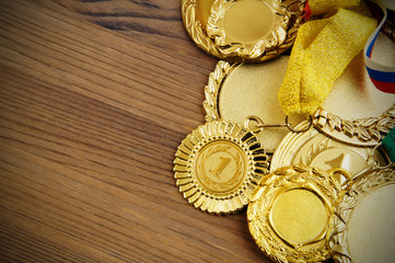 Gold medals with ribbons on wooden background with copyspace
