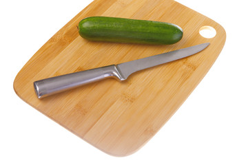 Ripe green cucumber and kitchen knife on cutting board