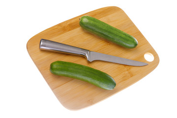 Pair of ripe green cucumbers and kitchen knife on cutting board