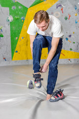 Rock climber puts on rocky shoes in a bouldering hall at a climbing gym