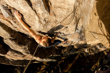 Climber Extreme climbs a rock on a rope with the top insurance, top view from above