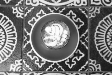 Charcoal latte on ornamental floor background. Trendy healthy organic drink.