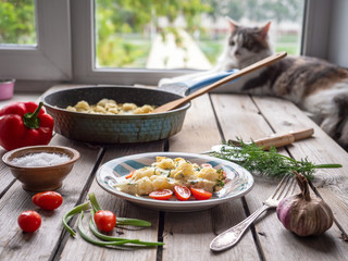 Baked cauliflower in seasoned eggs and krsany vegetables on an old wooden table, in the background lies a cat at the window