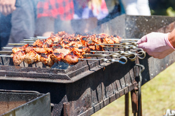 Grilled kebab cooking on metal skewer. Roasted meat cooked at barbecue.Traditional eastern dish, shish kebab. Grill on charcoal and flame, picnic, street food