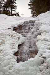 Fototapeta na wymiar Arethusa Falls Waterfall in the White Mountains of New Hampshire in Winter Crawford Notch State Park. Frozen and flowing water make the waterfall all the more magical. Ice sculptures formed by nature
