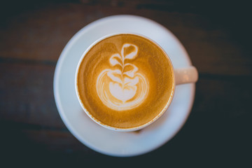 Latte hot coffee with foam milk art on a wooden table