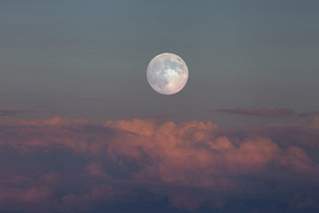 満月が夕陽で赤く染まる雲を照らす