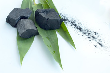 bamboo charcoal with green leaves on white background