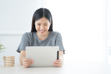 Young Asian woman using tablet at home and having breakfast in the morning .She reading on tablet.