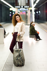 Young arabic woman waiting her train in a subway station.