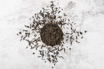 Dried tea is poured into a white ceramic cup on a marble table. View from above. Layout.